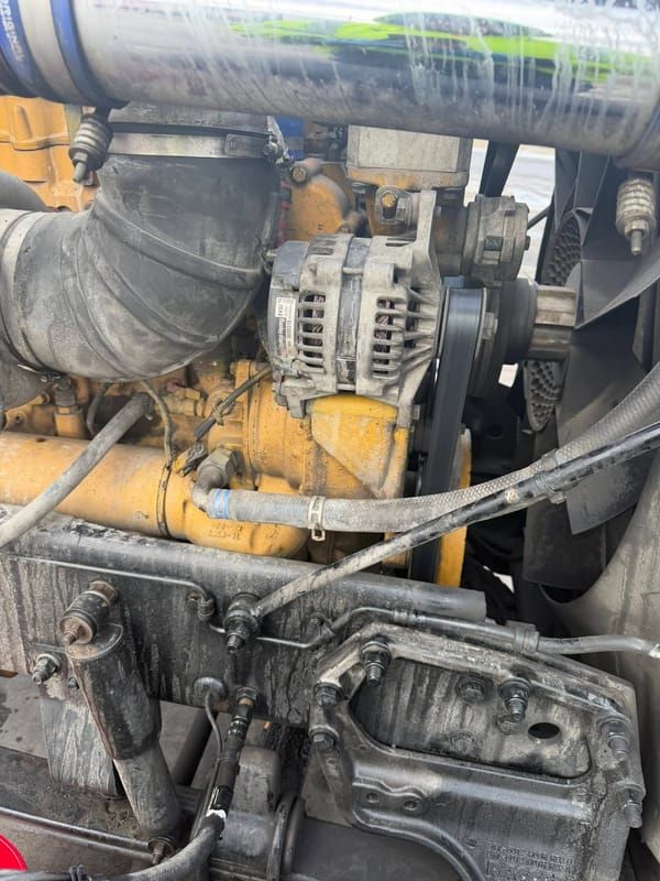 New alternator installed on a yellow Caterpillar diesel engine